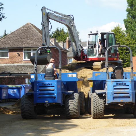 Two dumper trucks work in parallel to transfer the sand from the car park onto the pitch.
