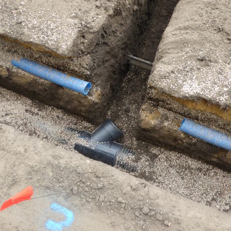 A collar on the main drainage pipe ready to be connected to the lateral 100mm diameter drains.   The blue pipe is a section of the old drainage system.
